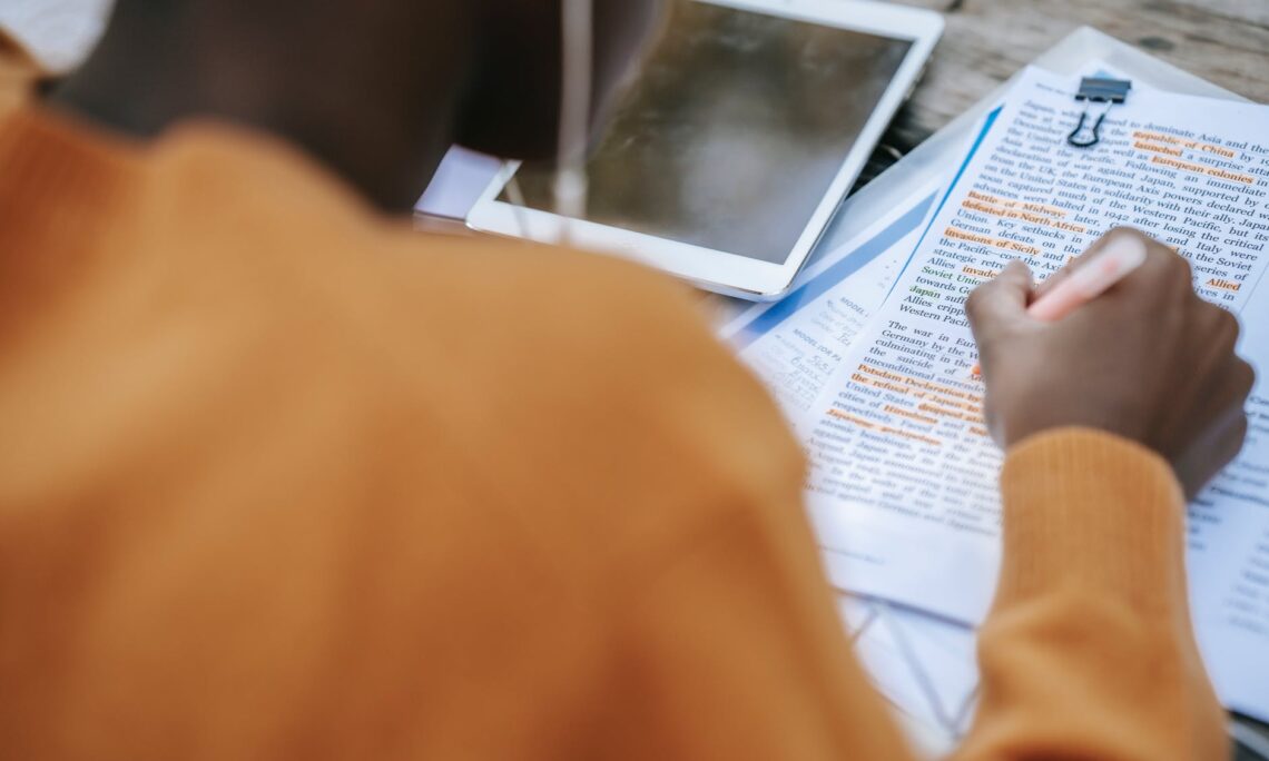 black person in earphones highlighting words in text on paper