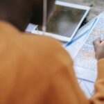 black person in earphones highlighting words in text on paper