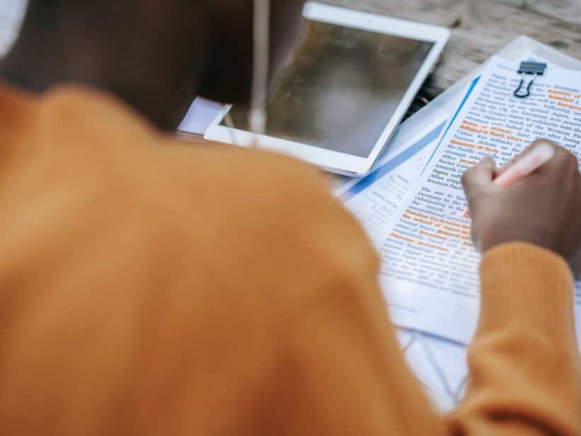 black person in earphones highlighting words in text on paper