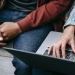 friends using laptop sitting on bench