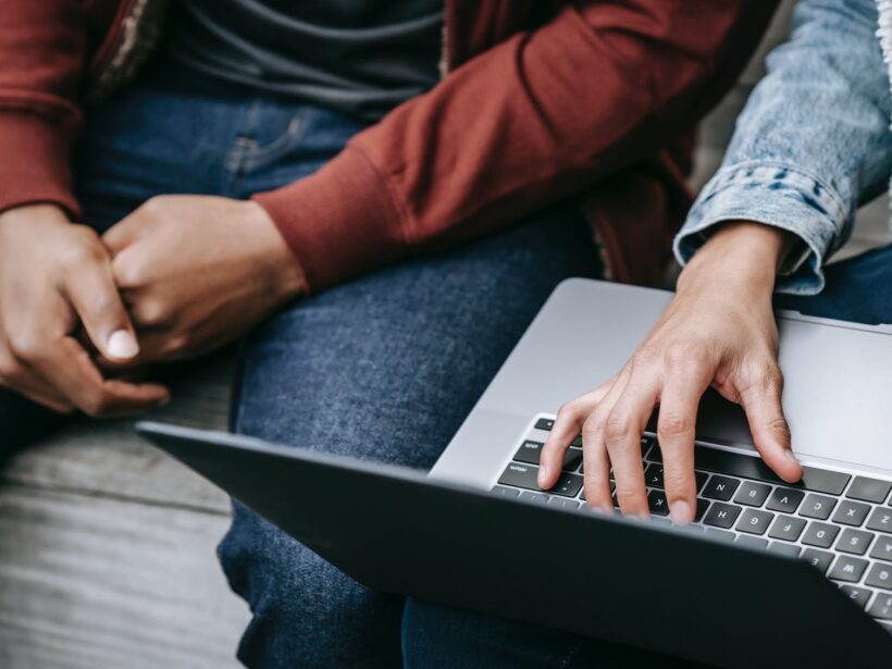 friends using laptop sitting on bench