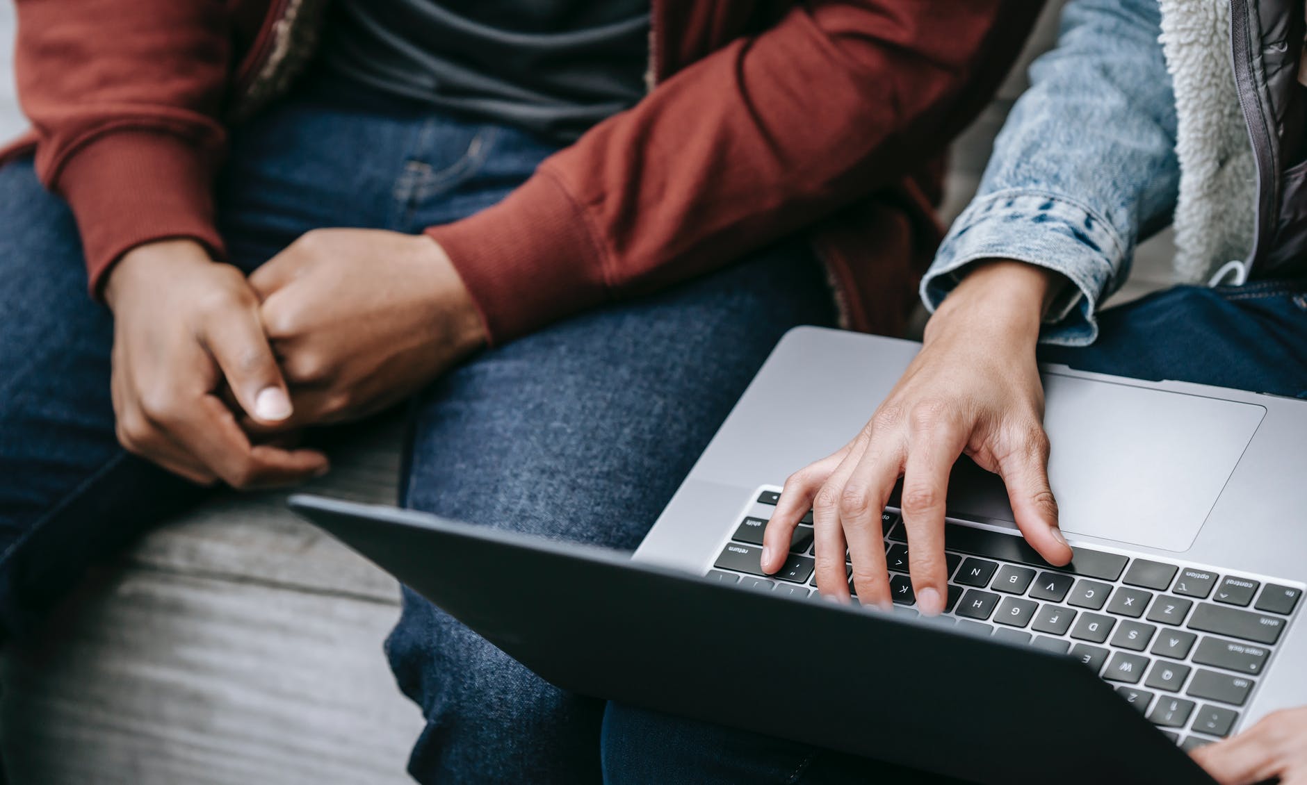 friends using laptop sitting on bench